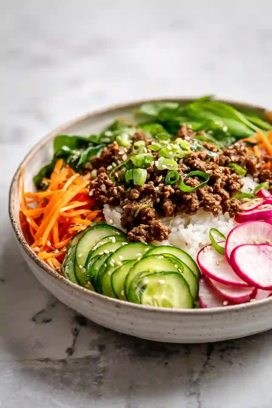 Korean Ground Beef Bowls Quick & Healthy Dinner A vertical image of Korean-inspired ground beef bowl with rice and fresh vegetables