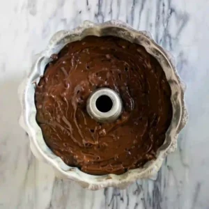 Chocolate peppermint bundt cake batter with chocolate chips poured evenly into a greased bundt pan